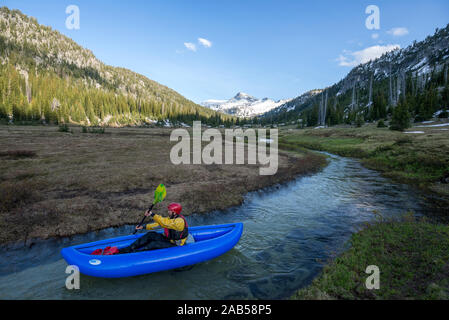 Pagaiando un kayak gonfiabili su un flusso attraverso un prato subalpina in Oregon Eagle di deserto Cap. Foto Stock