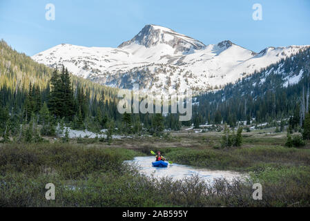 Pagaiando un kayak gonfiabili su un flusso attraverso un prato subalpina in Oregon Eagle di deserto Cap. Foto Stock