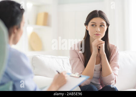 Interessati giovane donna ascoltando con attenzione psicoterapeuta Foto Stock