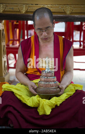 Un monaco tibetano si siede con grani di preghiera di fronte al Bodhi tree in Bodhgaya,, Bihar, in India. Foto Stock