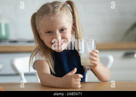 Funny happy carina ragazza di capretto tenere il vetro bere latte fresco Foto Stock