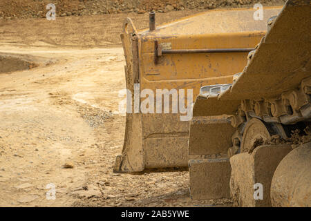 Escavatore riassume il suolo sul sito in costruzione a secco di stagione estiva Foto Stock