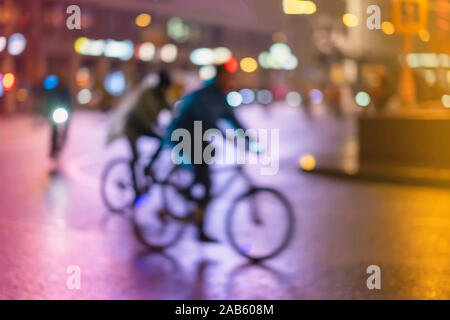 Abstract irriconoscibile la gente, equitazione biciclette, night city, illuminazione bokeh, motion blur. Uno stile di vita sano, attività di svago di concetto. Foto Stock