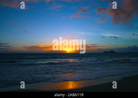 Rising Sun all'orizzonte al di sopra di un calmo mare o sul mare. Sul cielo blu bianco delle nuvole Foto Stock