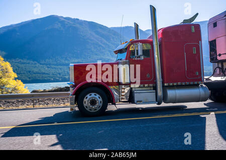 Rosso scuro cofano classic American big rig semi carrello con scarico verticale tubi per il trasporto refrigerato semi ondulato rimorchio con frigorifero onu Foto Stock