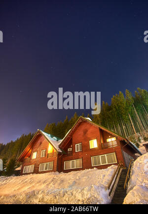 Casa di montagna nella neve durante la notte Foto Stock