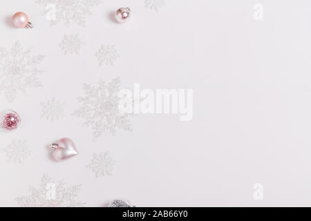 Composizione di natale. Cornice fatta di palline e fiocchi di neve pastello su sfondo grigio. Foto Stock