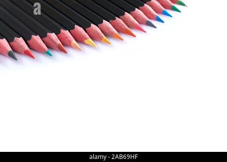 Close-up di una riga isolata di nero matite colorate contro uno sfondo bianco con spazio di copia Foto Stock
