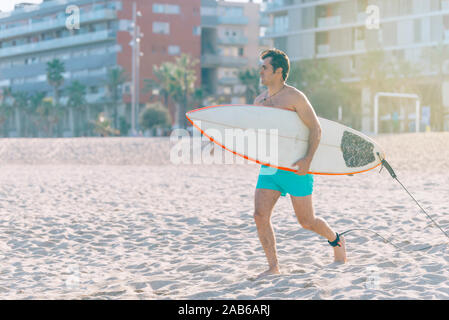 Spiaggia Sport acquatici surf uomo con il corpo con la tavola da surf in esecuzione felice durante le vacanze estive Vacanze con sole. Foto Stock