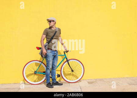 Uomo in posa con il suo ingranaggio fisso bicicletta indossando occhiali da sole Foto Stock