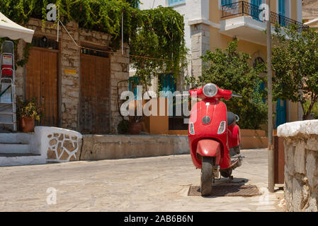 Symi Island, Grecia - 27 Giugno 2019: vista colorate strade di Symi Island con red vespa moto, Grecia Foto Stock