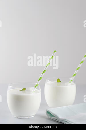 Ayran, yogurt drink (kefir, lassi) con foglia di menta in due bicchieri. Rinfrescanti drink freddo.orientamento verticale con spazio copia,fuoco selettivo. Foto Stock