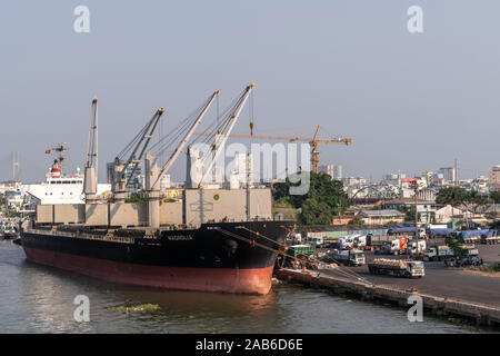 La città di Ho Chi Minh, Vietnam - Marzo 13, 2019: Downtown port sulla canzone Sai Gon river al tramonto. Nero e rosso Magnolia carichi alla rinfusa nave al molo con tutti h Foto Stock