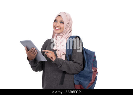 Il hijab studente cerca di pensare con tablet e portante un sacchetto Foto Stock