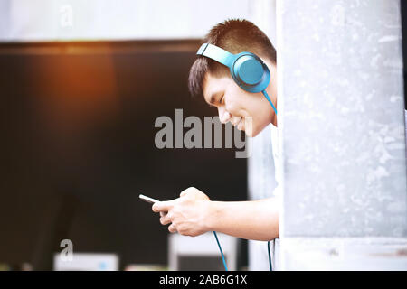 I giovani simpatici uomini belli sorridente e ascolto di musica guardando il telefono Foto Stock