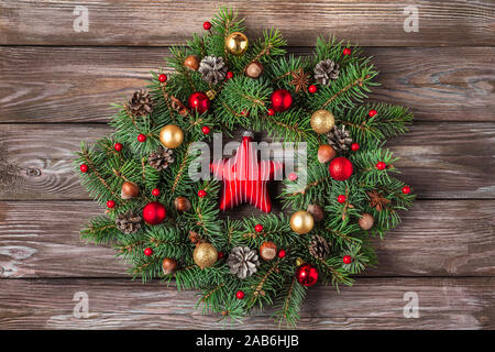 Ghirlanda di Natale fatto di Abete rami, decorazioni, stella del giocattolo, pigne e i dadi su sfondo di legno. Natale, inverno, anno nuovo concetto. Appartamento Foto Stock