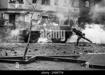 Protesta che lancia la bomba molotov al carro armato della polizia durante gli scontri tra la polizia e i manifestanti a Vicuña Mackenna durante gli ultimi scontri a Santiago Foto Stock