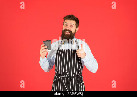 Miglior gusto mai. elegante fiducioso barista maschio bere il caffè. uomo barbuto tenere take away caffè. brutale cameriere cafe. uomo maturo sfondo rosso. Esperti servo. barista hipster chef grembiule. Foto Stock