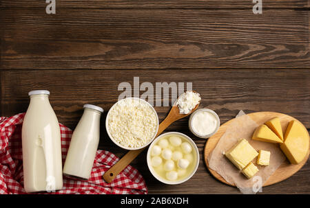 I latticini e prodotti da latte acido su una tavola di legno scuro dello sfondo rustico. Latte, kefir, yogurt, burro, formaggio assortimento. Disposizione piatta vista dall'alto. Copia dello spazio. Hor Foto Stock