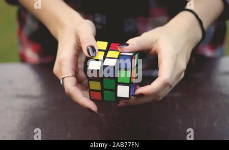 Vancouver, Canada - Ottobre 1,2019: una giovane donna sta cercando di risolvere il cubo di Rubik su una tavola di legno nel Parco di Stanley Foto Stock