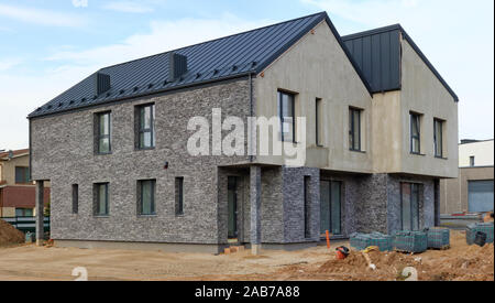 Standard di produzione di massa incompiuta simmetrico a due piani casa rurale per quattro giovani famiglie da mattoni grigio Foto Stock