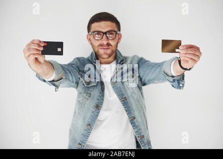 Giovane maschio bello business executive in abbigliamento casual in possesso di una carta di credito nelle tasche su uno sfondo bianco. Il concetto di negoziazione sul Foto Stock