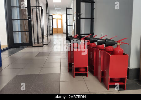 Estintore sul posto di lavoro in ufficio. Nuovo serbatoio rosso di estintore in un box Foto Stock