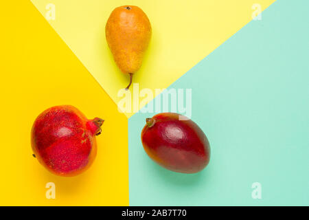 Layout creativo fatto di frutti. Lay piatto. Pera, mango e melograno su sfondo colorato con copia spazio. Foto Stock