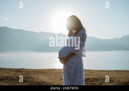 Donna incinta mentre tiene il suo stomaco Foto Stock