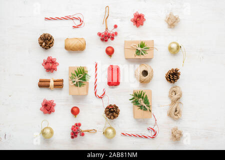 Creative sullo sfondo di Natale di vari oggetti comprese confezioni regalo, bastoncini di cannella, bacche decorativi sul tavolo bianco, il fuoco selettivo Foto Stock