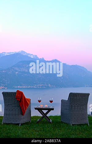 Poltrone e vino rosso con la vista del lago di Como al tramonto, Lombardia, laghi italiani, l'Italia, Europa Foto Stock