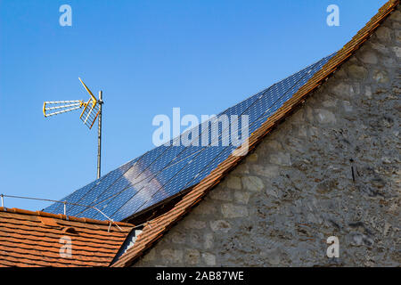 Vecchia casa con pannelli solari e antenna TV installato sul tetto di close-up Foto Stock