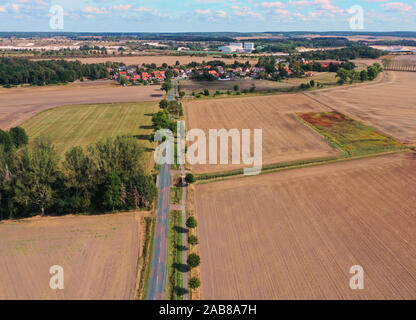 Vista aerea di un paese dritta strada che conduce ad un villaggio in un paesaggio culturale di monotono seminativi. Foto Stock