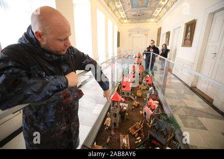 Altenburg, Germania. 26 Nov, 2019. Mostra Organizzatore Oliver Schaffer sorge accanto ad un espositore con Playmobil figure con il motto "Altenburger Prinzenraub' nella mostra "Playmobil Inverno magico nel Residenzschloss Altenburg'. Dal 1 Dicembre al 15 marzo 2020, i visitatori possono ammirare oltre 5000 installato figure e oltre 50.000 singole parti. Credito: Bodo Schackow/dpa-Zentralbild/dpa/Alamy Live News Foto Stock