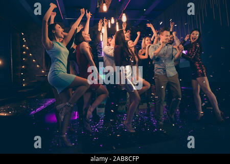 Lunghezza piena dimensione corpo foto di allegro affascinante giovane e bella gente divertendosi al night club dancing in caduta di coriandoli pioggia sotto permanente Foto Stock