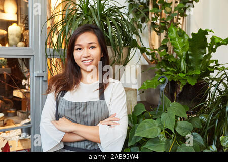 Giovane donna asiatica come fioraio in formazione in negozio di fiori Foto Stock