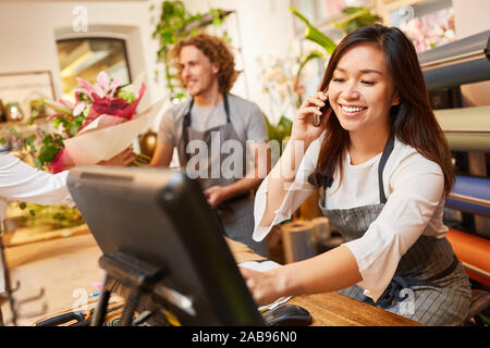 Commessa o fioraio prende fine sul telefono Foto Stock