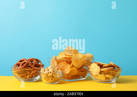 La birra snack, patatine, cracker in una ciotola su sfondo giallo contro sfondo blu, spazio per il testo Foto Stock