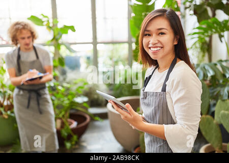 Giovani fioraio con computer tablet, inventario o ordinare online Foto Stock