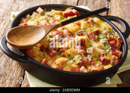 Strata casseruola di pane con prosciutto, cipolle, formaggio e le uova in una pentola sul tavolo orizzontale. Foto Stock