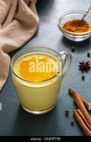 La tradizione indiana bere latte dorato con la curcuma e spezie su uno sfondo blu. Foto verticale Foto Stock