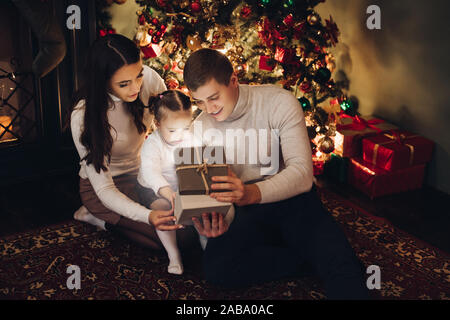 Famiglia Natale apertura presente insieme. camera decorata per Natale. Foto Stock