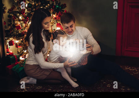 Famiglia Natale apertura presente insieme. camera decorata per Natale. Foto Stock