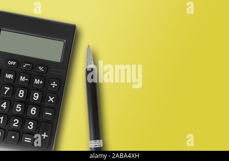 Vista superiore della calcolatrice tascabile e penna su sfondo giallo, finanza e contabilità modello di concetto Foto Stock
