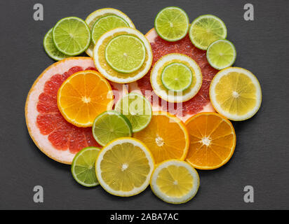 Sfondo di frutta. Fette di agrumi su un tavolo di pietra. Appartamento laico, vista dall'alto. Succose arance mature, mandarino, pompelmo, lime e limone su un backgro grigio Foto Stock