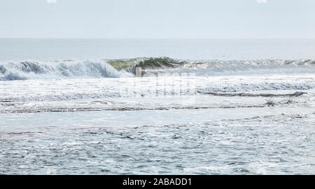 Fumoso si filtra la luce solare che colpisce onde come esse rotolano in su Ocean City Beach Ocean City, Maryland, Stati Uniti d'America. Foto Stock