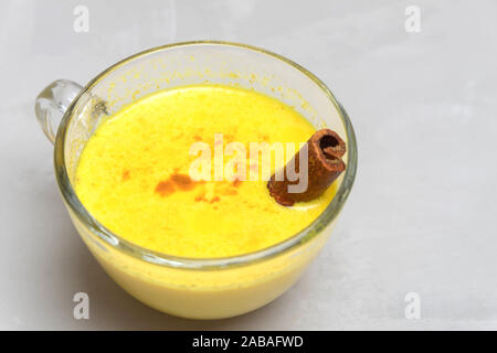 Primo piano immagine di speziato indiano bere curcuma golden il latte con la stecca di cannella sul cemento grigio sfondo Foto Stock