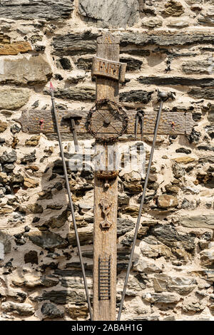 Croce con i simboli della Passione di Cristo, pinza, scaletta, martello, calice, lancia, la corona di spine, ROOSTER, testo INRI. Vernazza village, Italia Foto Stock