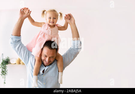 Ragazza carina a cavallo di suo padre le spalle Foto Stock