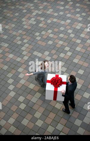 Executive sorprese la sua amata con un enorme regalo con un grande arco rosso Foto Stock